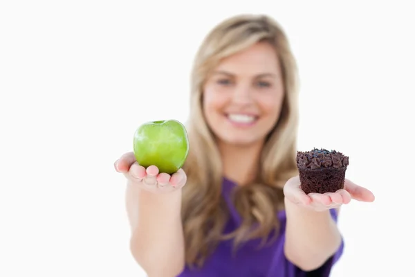 A fruit and a muffin being held by a blonde woman — Stock Photo, Image