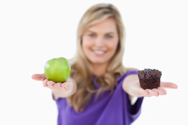 Ein grüner Apfel und ein Muffin, der von einer jungen Frau gehalten wird — Stockfoto