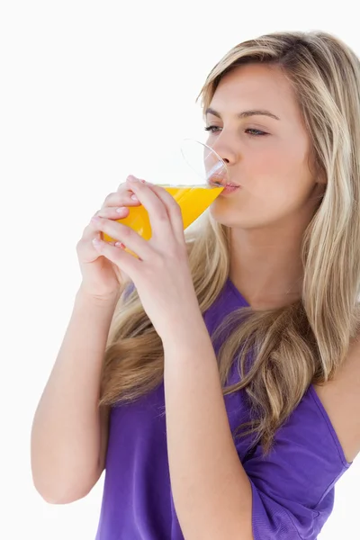 Jovem loira bebendo um suco de laranja — Fotografia de Stock