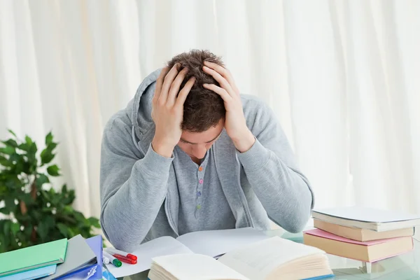 Distressed student in front of his books — Stock Photo, Image