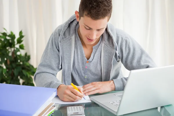 Gülümseyen öğrenci ile bir dizüstü bilgisayar ödevini yapıyor — Stok fotoğraf
