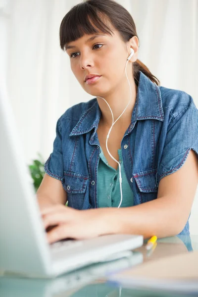 Female student doing her homework with music — Stock Photo, Image