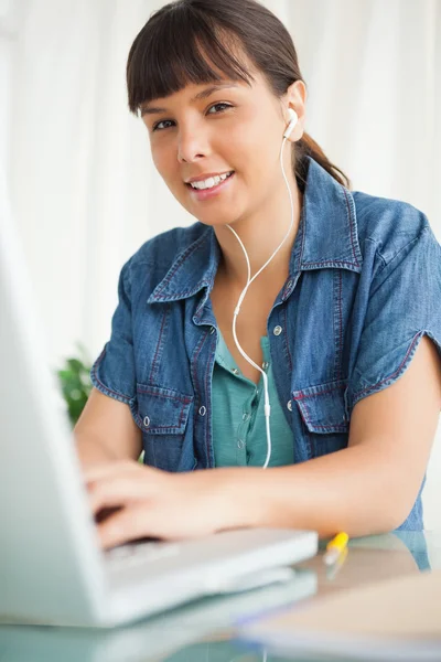 Portrait of a female student doing her homework with music — Stock Photo, Image