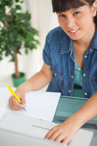 Porträt einer süßen lächelnden Studentin, die ihre Hausaufgaben macht — Stockfoto