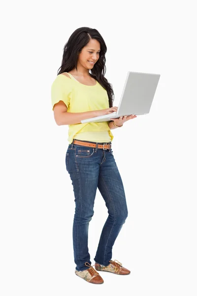 Sorridente studente latino in piedi con un computer portatile — Foto Stock