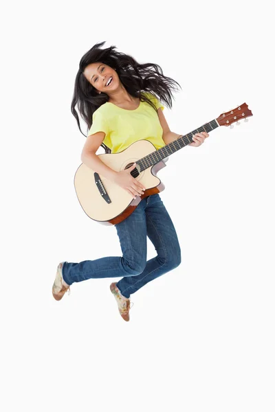 Νέα Λατίνος γυναίκα που κρατά μια κιθάρα ενώ άλμα — Φωτογραφία Αρχείου