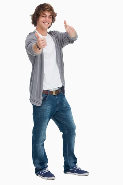 Улыбающийся студент-мужчина, ставящий большие пальцы вверх — стоковое фото