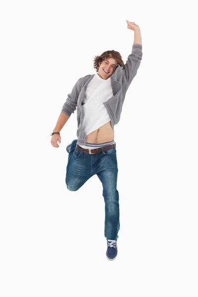 Estudante do sexo masculino posando por saltar com um braço levantado — Fotografia de Stock