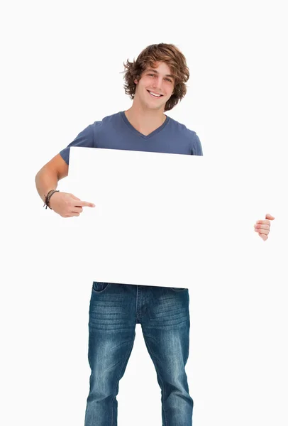 Male student posing while holding and pointing a white board — Stock Photo, Image