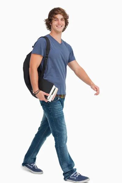 Mannelijke student met een rugzak bedrijf boeken tijdens het wandelen — Stockfoto