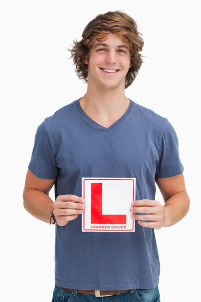 Joven sonriente sosteniendo una señal de conductor aprendiz — Foto de Stock