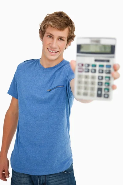 Улыбающийся молодой человек показывает калькулятор — стоковое фото