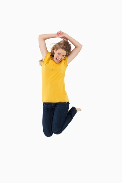 Young woman in yellow shirt jumping — Stock Photo, Image