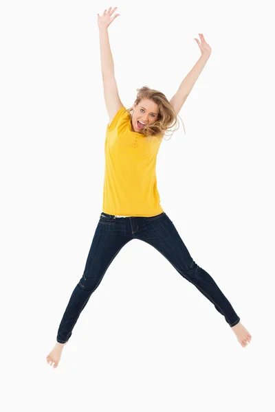 Jovem loira de camisa amarela pulando — Fotografia de Stock