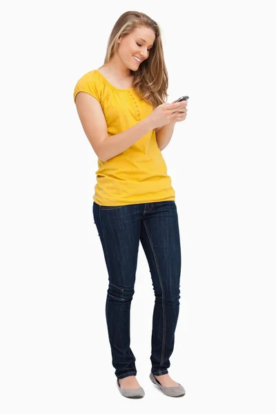 Attraktive blonde Frau lächelt, während sie ihr Handy benutzt — Stockfoto