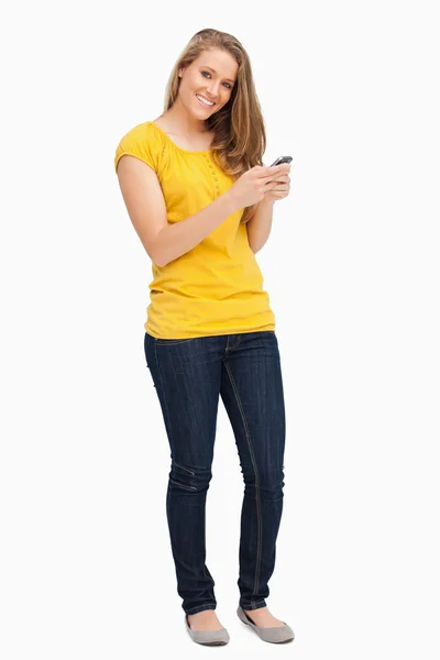 Atractiva mujer rubia posando mientras usa su teléfono celular —  Fotos de Stock