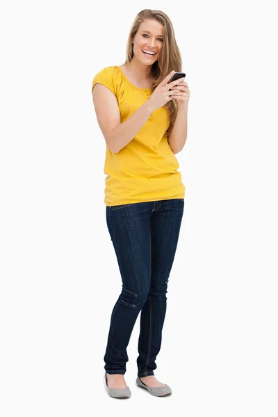 Retrato de uma mulher loira rindo enquanto usa seu celular — Fotografia de Stock