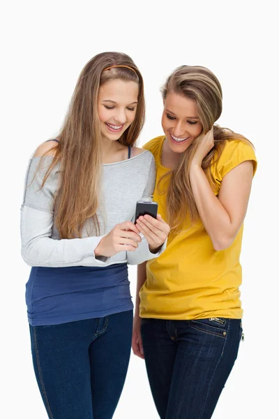 Zwei Studentinnen lächeln, während sie ein Handy betrachten — Stockfoto