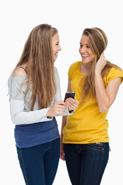 Две студентки смеются, держа в руках мобильник. — стоковое фото