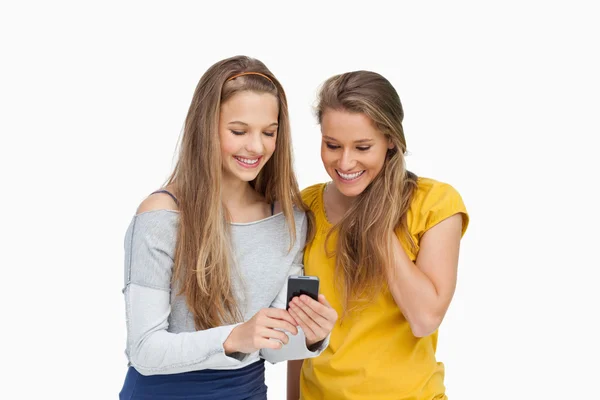Два улыбающихся студента смотрят на экран мобильного телефона — стоковое фото