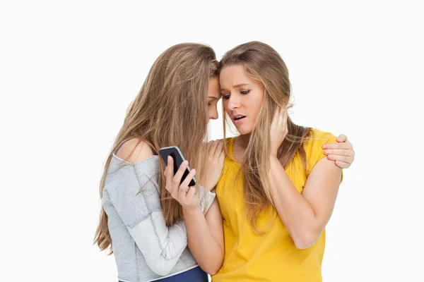 Upset young woman looking her cellphone consolded by her friend — Stock Photo, Image