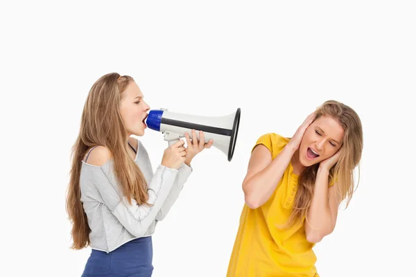 Студентка-блондинка кричит громкоговорителем на другую девушку — стоковое фото