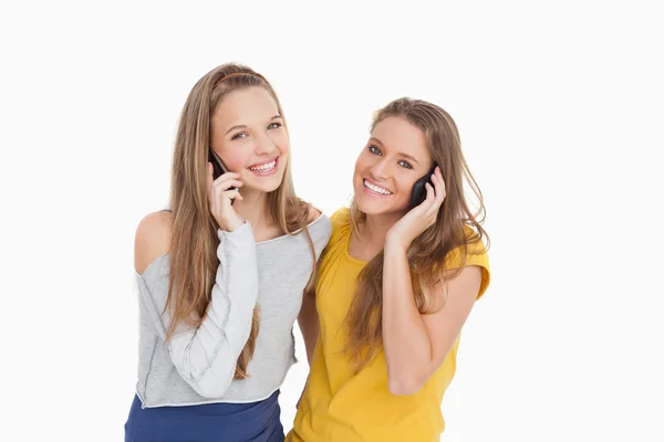 Zwei junge Frauen lächeln am Telefon — Stockfoto