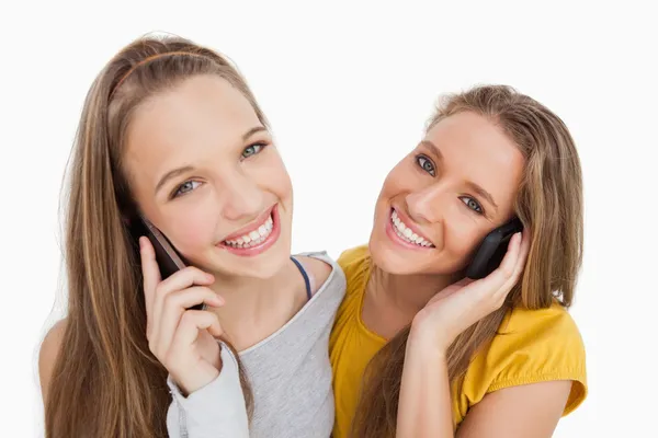Primer plano de dos mujeres jóvenes sonriendo por teléfono —  Fotos de Stock