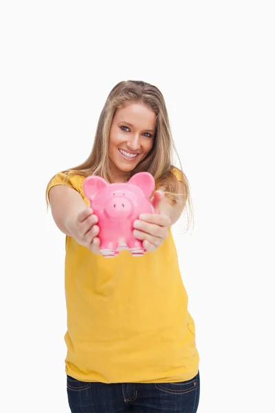 Young blond woman tending a piggy-bank — Stock Photo, Image