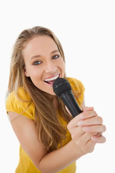 Close-up de uma loira cantando com um microfone — Fotografia de Stock