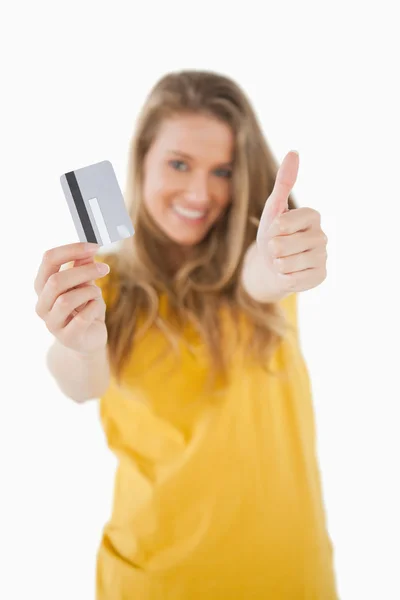 Retrato de una estudiante rubia atendiendo una tarjeta de crédito con el thum — Foto de Stock