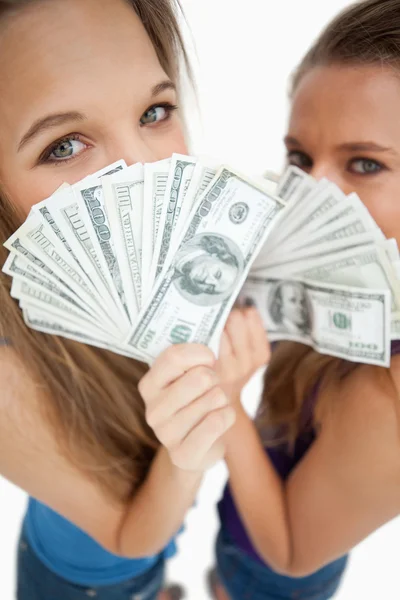 Vue en angle élevé de deux jeunes femmes derrière des dollars — Photo