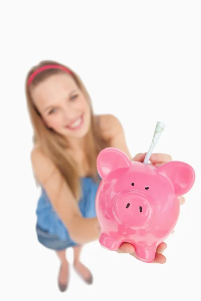 Fischaugenaufnahme einer jungen Frau, die Geld in ein Sparschwein legt — Stockfoto
