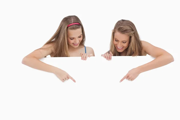 Gros plan de jeunes femmes tenant et pointant un panneau vierge — Photo