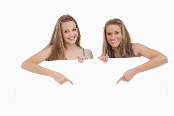 Portrait of young women holding and pointing a blank sign — Stock Photo, Image