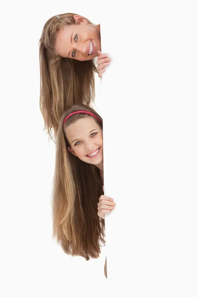 Gros plan de deux étudiants cheveux longs derrière un panneau vierge — Photo