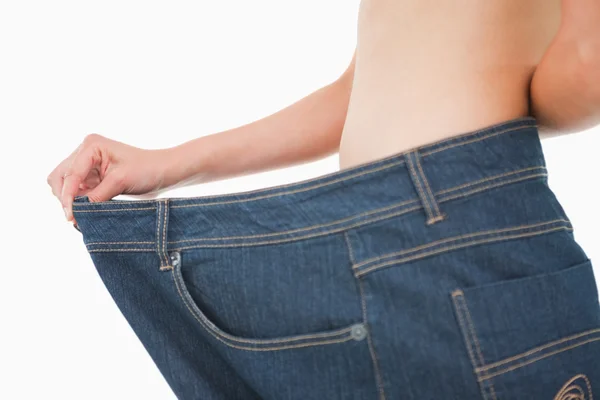Närbild av en kvinna mage i en för stor byxor — Stockfoto