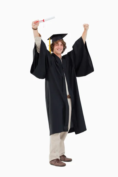 Studente maschio in vestaglia laureato alzando le braccia — Foto Stock