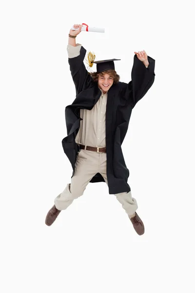 Male student in graduate robe jumping — Stock Photo, Image