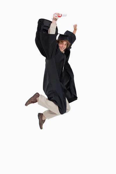 Happy male student in graduate robe jumping — Stock Photo, Image