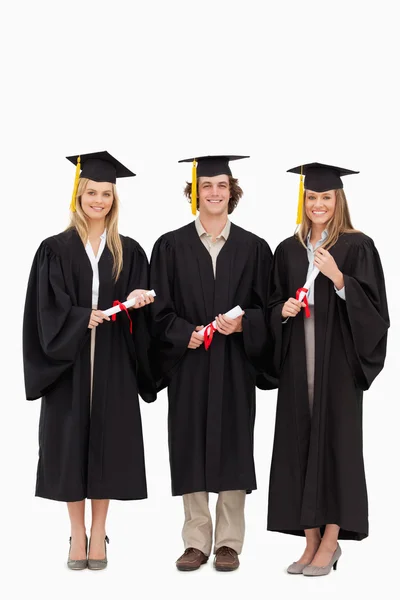 Três estudantes em roupão de pós-graduação com diploma — Fotografia de Stock