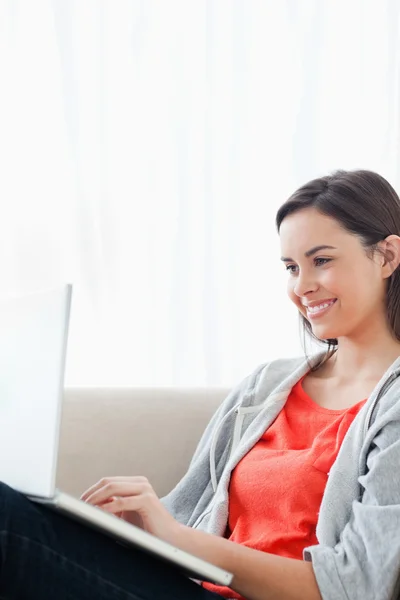 Femme souriante utilisant son ordinateur portable sur le canapé — Photo