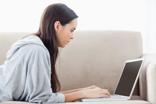 Een vrouw die liggend op de Bank met haar laptop — Stockfoto