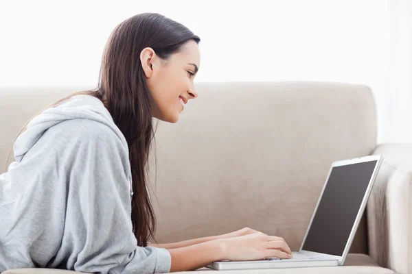 Ένα χαμογελαστό γυναίκα που βρίσκεται επάνω αυτήν μπροστινός χρησιμοποιώντας το laptop — Φωτογραφία Αρχείου