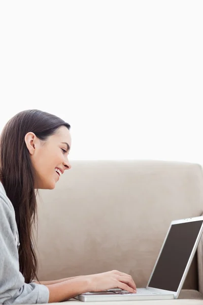 Une femme rieuse allongée sur son canapé avec son ordinateur portable — Photo
