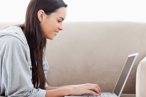 Žena psaní na svém laptopu vleže na gauči — Stock fotografie