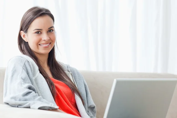 Half length shot of a smiling woman on the couch looking into th — Stock Photo, Image