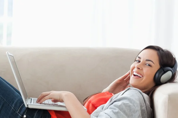 Смеющаяся женщина, стоящая на диване, глядя в камеру — стоковое фото