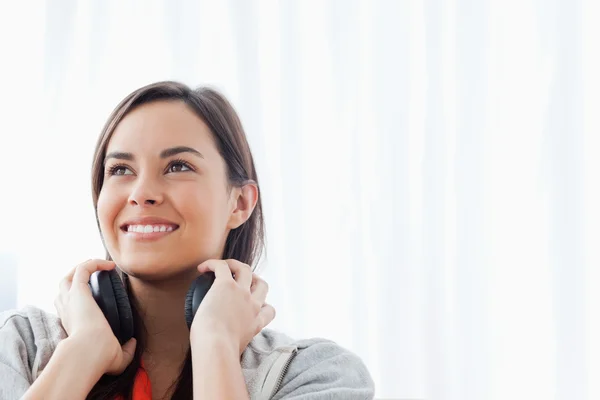 Een vrouw op zoek naar iets boven en lachend met koptelefoon — Stockfoto