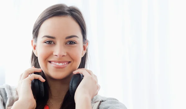 Eine lächelnde Frau mit Kopfhörern blickt in die Kamera — Stockfoto